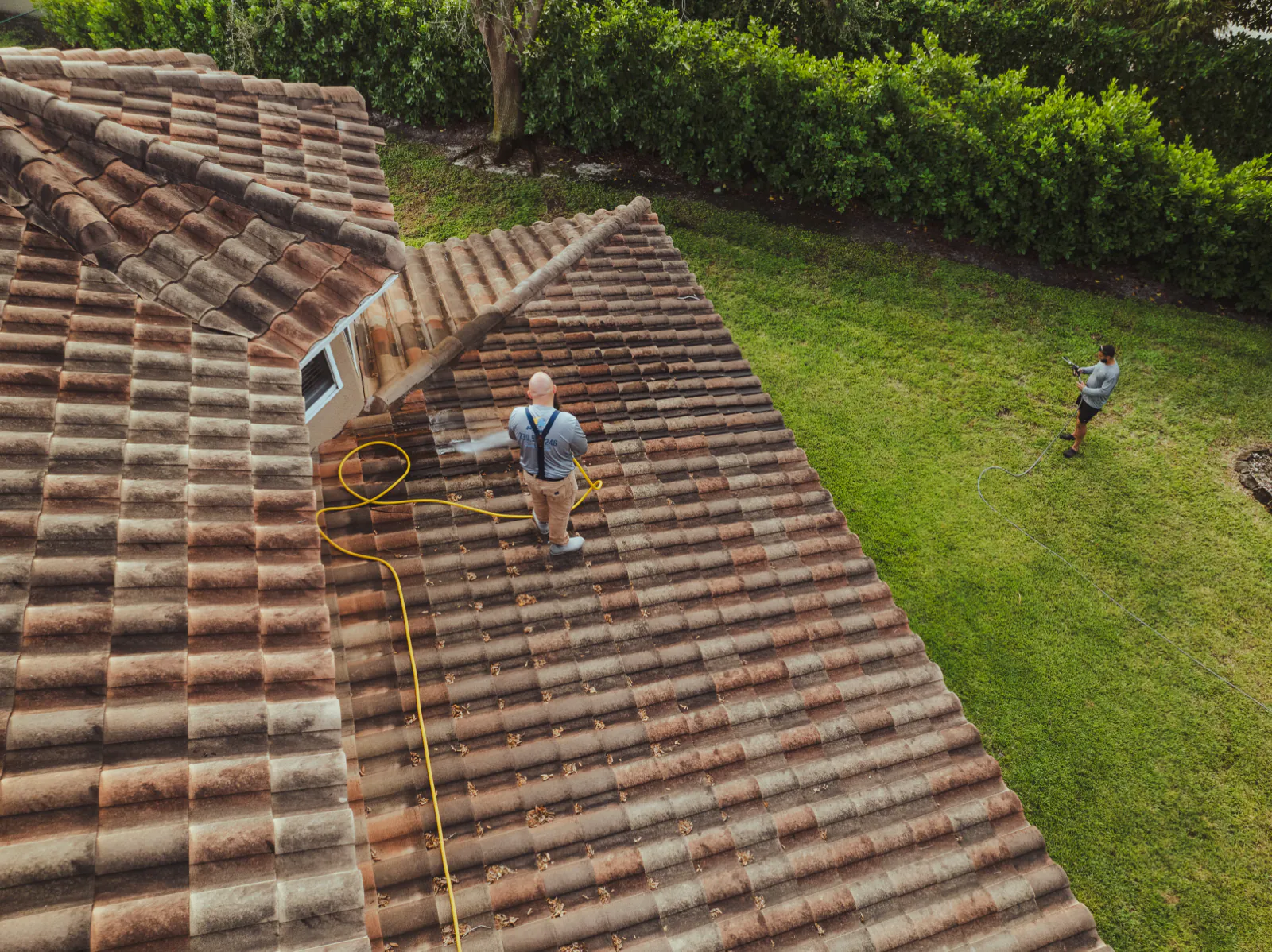 Soft wash solution being applied to the tile roof at low pressure