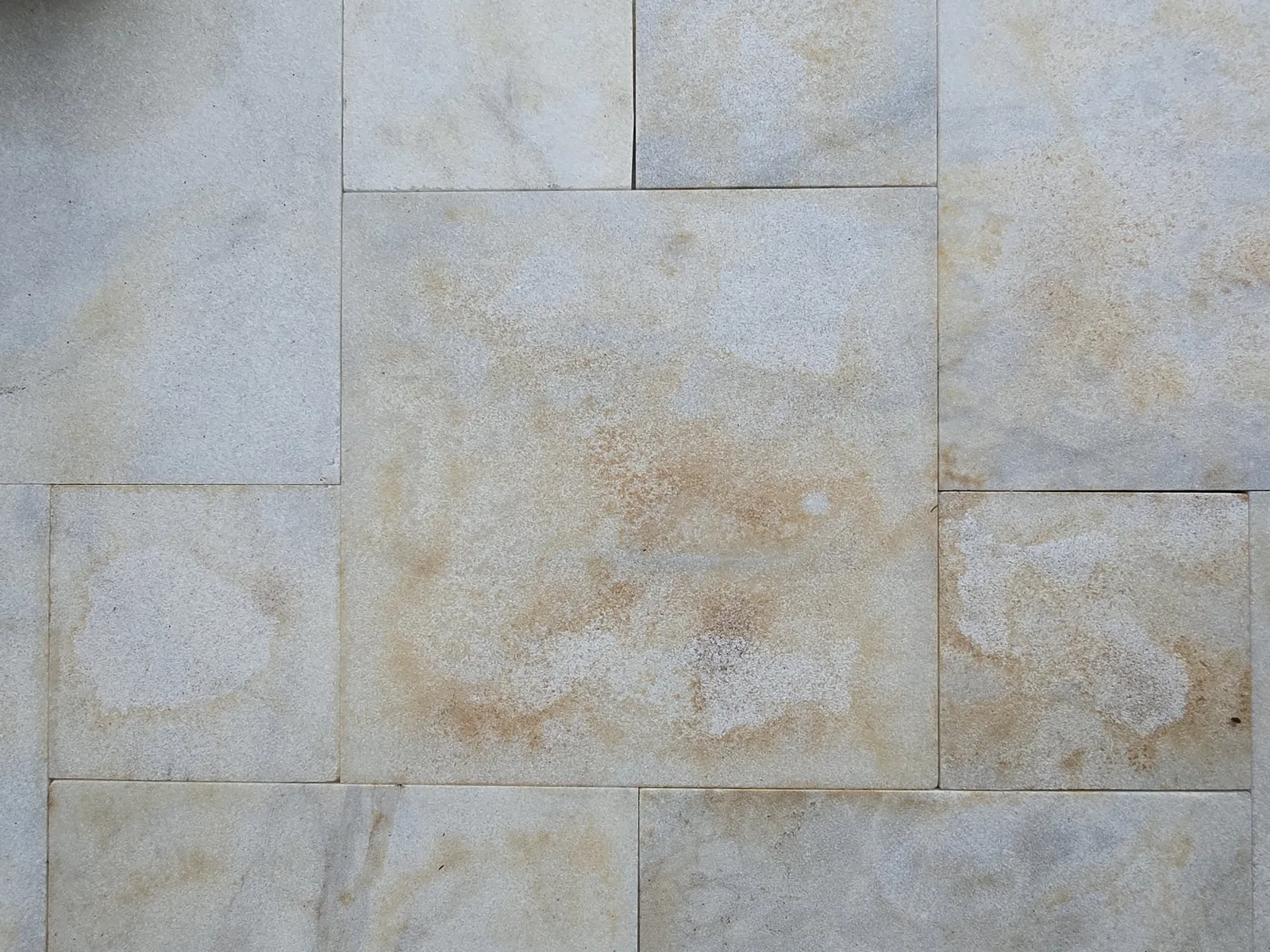 Close-up of orange iron stains on marble pavers before removal