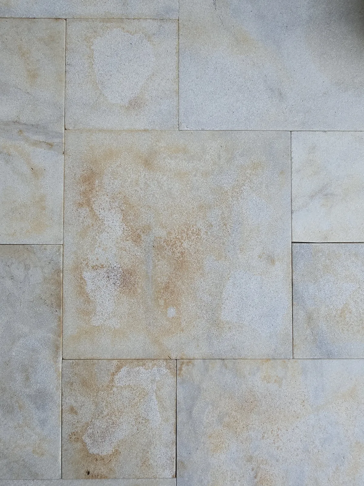Close-up of orange iron stains on marble pavers before removal