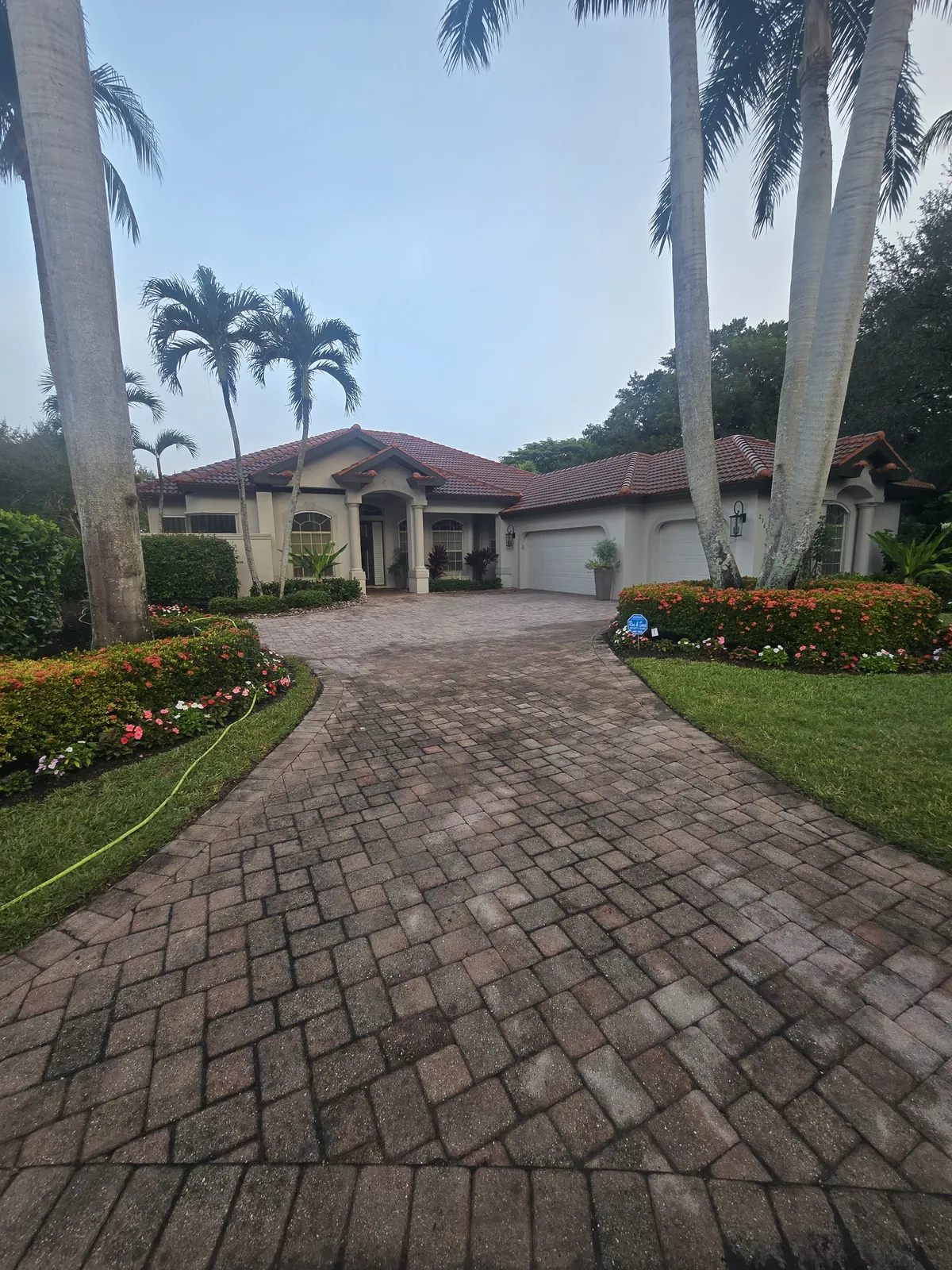 Paver driveway before stripping — uneven, blotchy old sealer