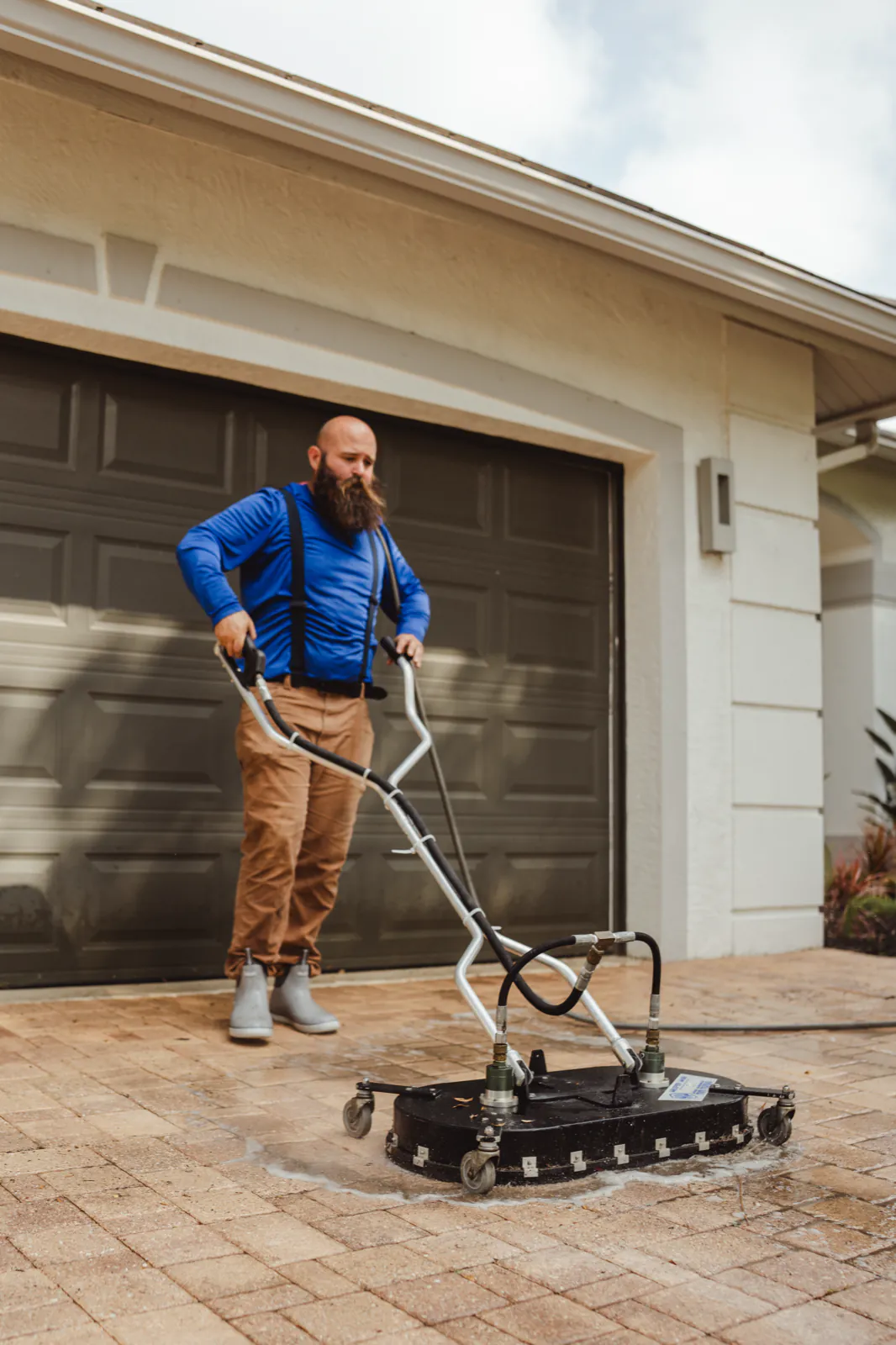 Surface cleaner deep-cleaning the paver driveway in front of the garage